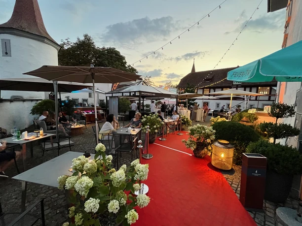 Schloss Whyer Roter Teppich und stilvoller Sitzbereich im Wasserschloss Wyher vor dem Open Air Kino. Tische, Pflanzen und warme Beleuchtung im Schlossambiente