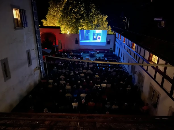 Blick auf das Open Air Kino im Wasserschloss Wyher mit Leinwand und Sitzreihen