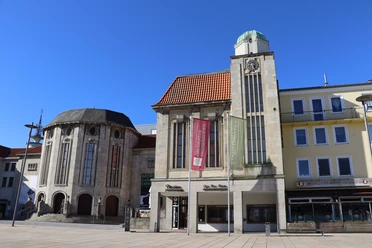 Stadttheater Bremerhaven mit Uhrenturm, Flaggen und Eingang zum Café Marlene.