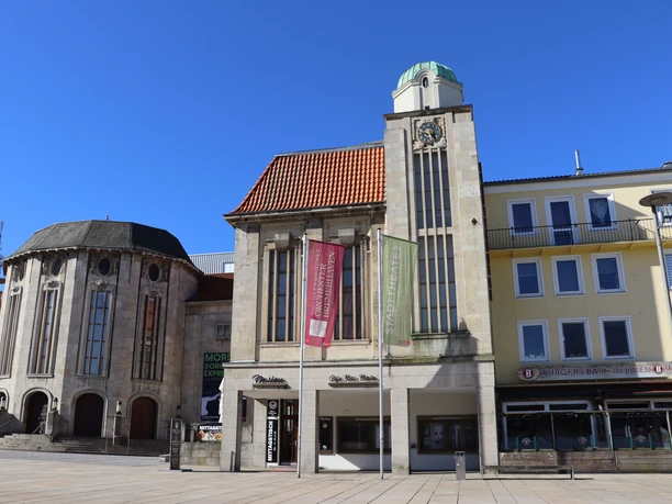 Marlene 7 (c) Taurean Reddeck_Erlebnis Bremerhaven_WEB.jpg Stadttheater Bremerhaven mit Uhrenturm, Flaggen und Eingang zum Café Marlene.