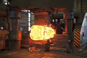 Stahlwerk Augustfehn II-glühendes Eisen-Apen-Foto Stahlwerk.jpg Eine massive Industriepresse formt einen hell glühenden Stahlrohling.