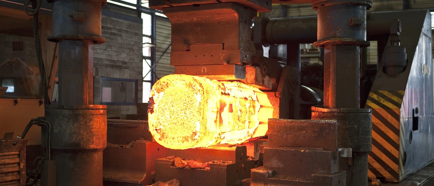 Stahlwerk Augustfehn II-glühendes Eisen-Apen-Foto Stahlwerk.jpg Eine massive Industriepresse formt einen hell glühenden Stahlrohling.