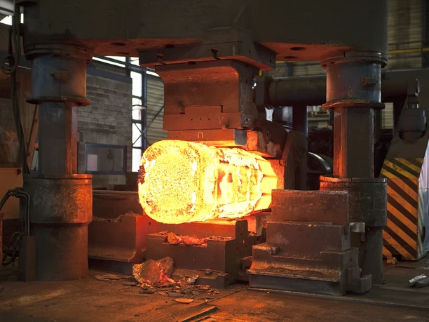 Stahlwerk Augustfehn II-glühendes Eisen-Apen-Foto Stahlwerk.jpg Eine massive Industriepresse formt einen hell glühenden Stahlrohling.
