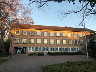 Rathaus Petershagen 2.jpg Dreistöckiges Rathaus Petershagen aus Backstein mit gepflastertem Vorplatz im Sonnenlicht.