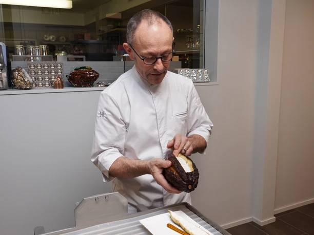 Cafe Amrein Chocolatier_Choco Workshop Michael Renggli präsentiert im Cafe Amrein Willisau eine geöffnete Kakaofrucht und erklärt den Ursprung der Schokolade während eines Choco-Seminars