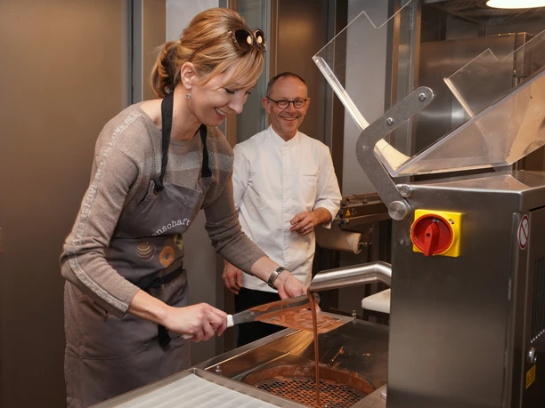 Cafe Amrein Chocolatier_Choco Workshop Eine Person arbeitet im Choco Seminar im Cafe Amrein Willisau an einer Maschine zur Verarbeitung flüssiger Schokolade