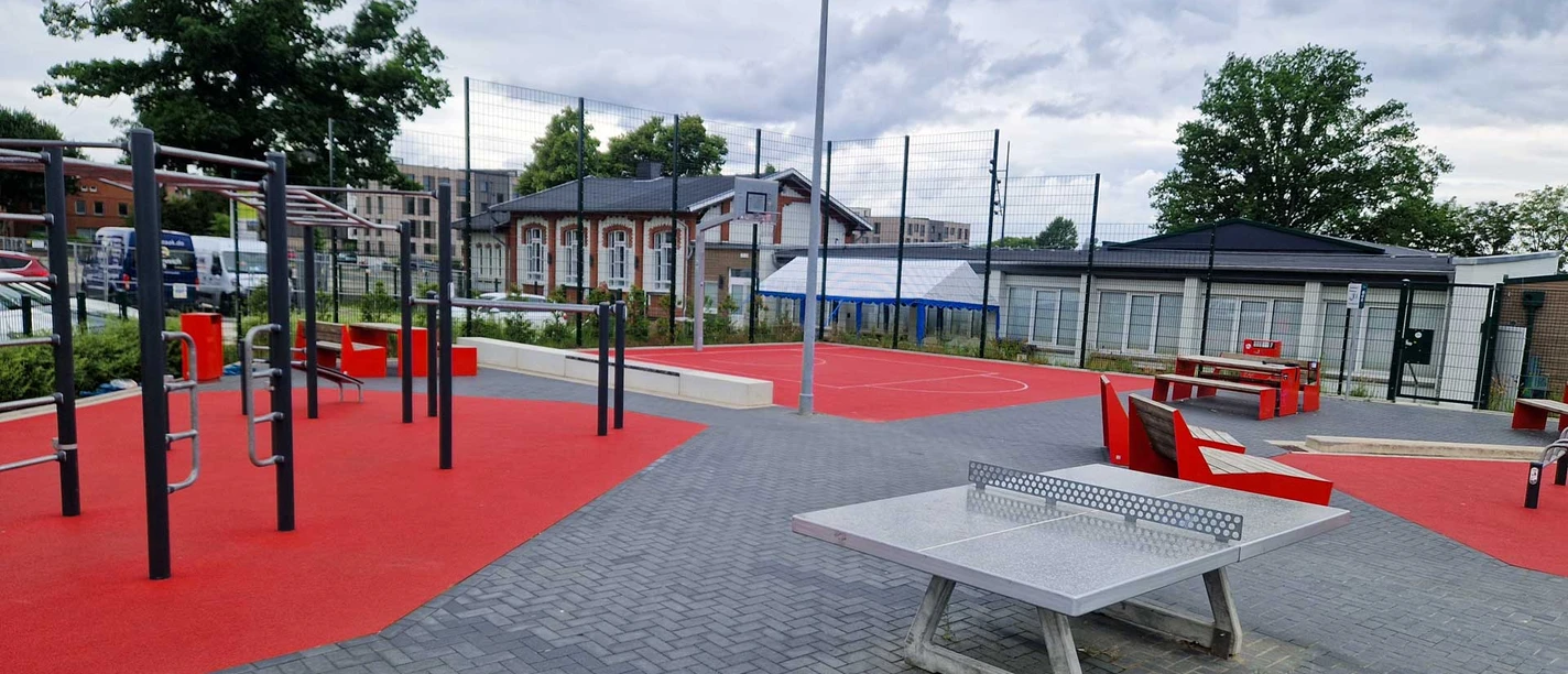 Trainieren auf der Allerinsel Outdoor-Sportplatz mit Tischtennisplatte, Fitnessgeräten und rotem Basketballfeld.