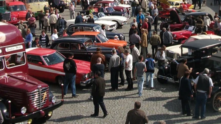 Oldtimertreffen_HD_16zu9.JPG Viele Menschen bewundern bunte Oldtimer auf einem sonnigen Platz mit Kopfsteinpflaster.