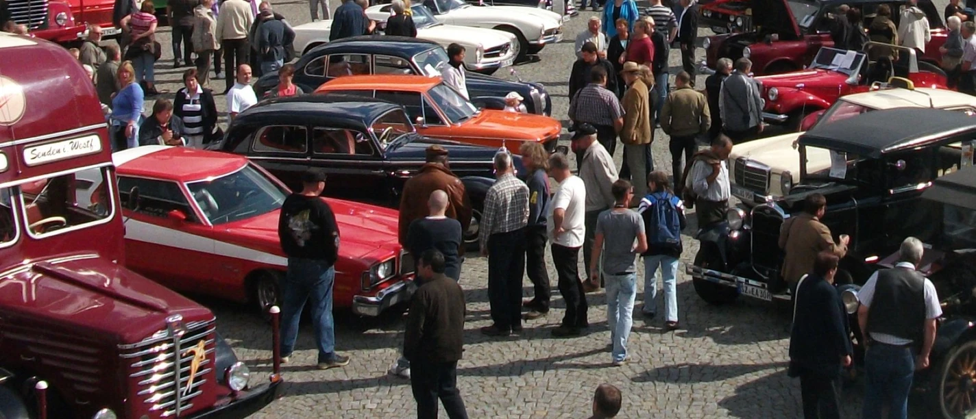 Oldtimertreffen_HD_16zu9.JPG Viele Menschen bewundern bunte Oldtimer auf einem sonnigen Platz mit Kopfsteinpflaster.