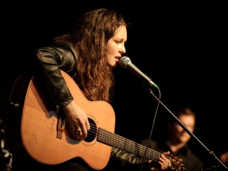 Joan Croker mit Gitarre und Mikrofon