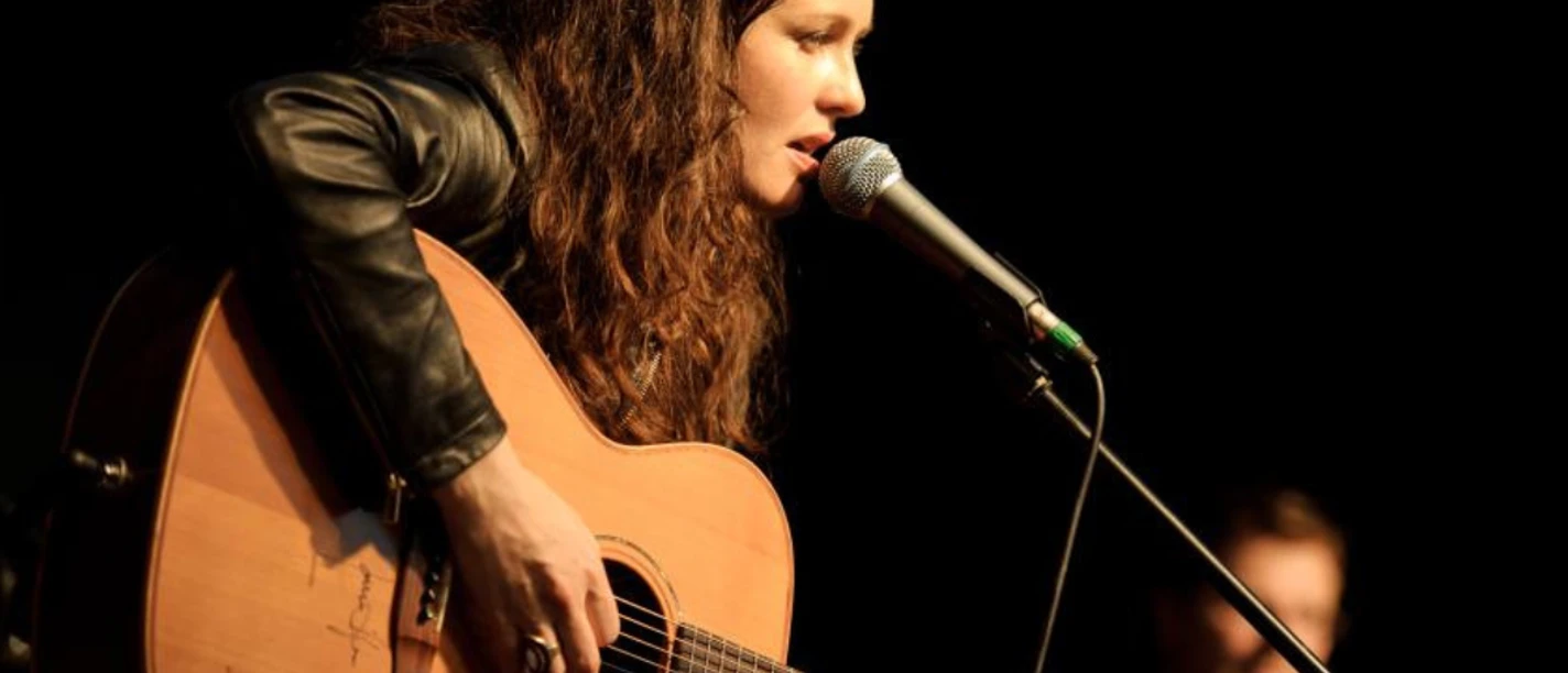Joan Croker mit Gitarre und Mikrofon