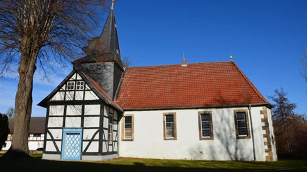 Kirche_Flachstöckheim_HD_16zu9.JPG Dorfkirche mit weißer Fassade, rotem Dach, markantem Fachwerk, blauer Tür und spitzem Kirchturm.