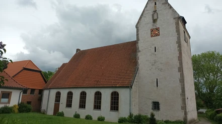 Kirche_Heerte_HD_16zu9.jpg Weiße Kirche St. Petri mit rotem Ziegeldach, dunklen Bogenfenstern und Turm mit Uhr.