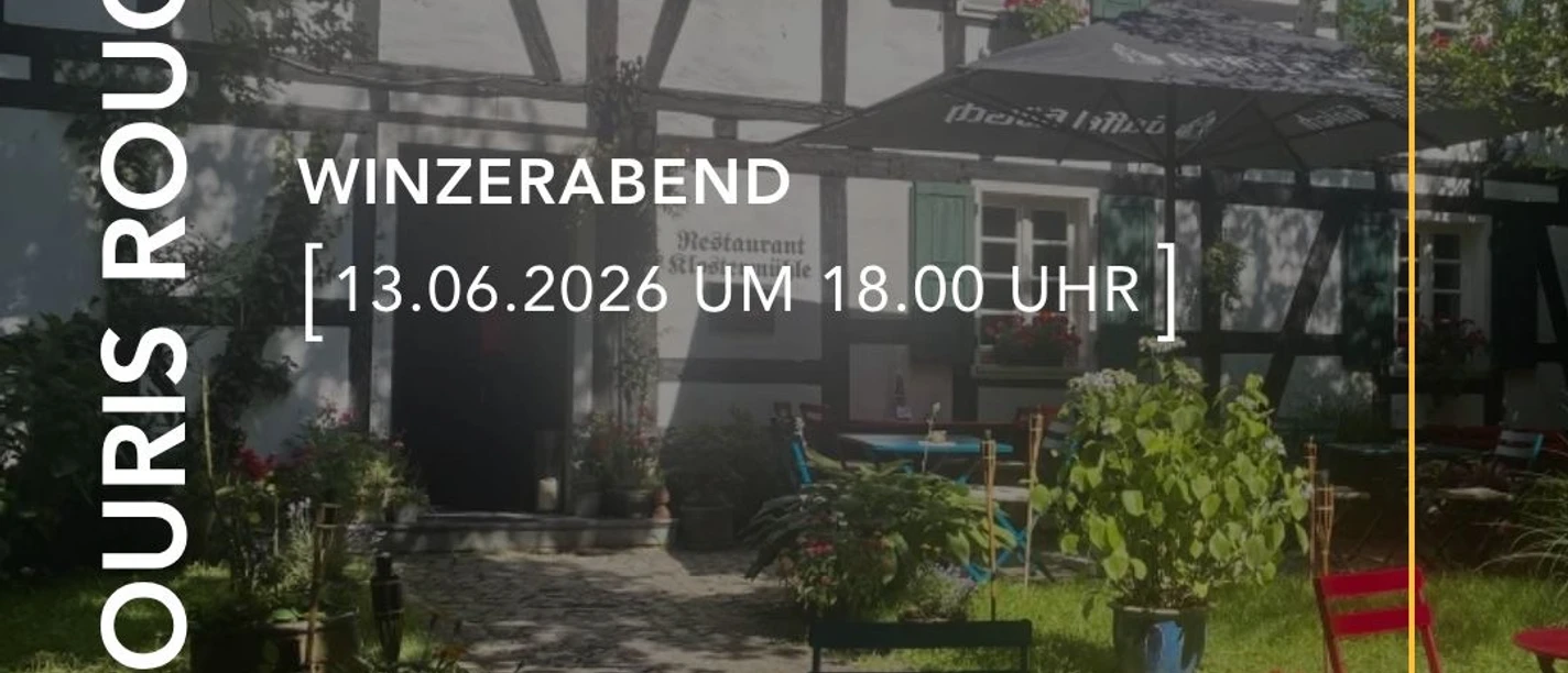 Winzerabend Schattiger Hof mit bunten Sitzmöbeln vor einem historischen Fachwerkhaus im Grünen.