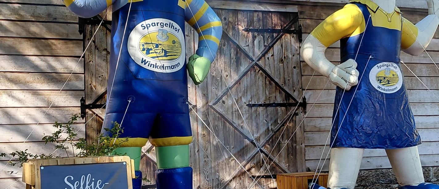Spargelhof Winkelmann Zwei große Spargelfiguren vor Holzscheune, Selfie-Station beim Hoffest