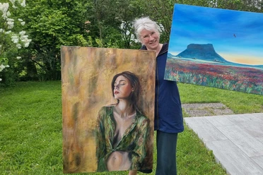 Frau hält zwei Gemälde: eines mit einer Frau und eines mit einer Landschaft.
