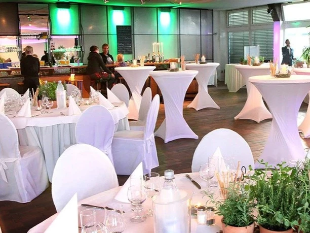 Weihnachten_Tafelfreuden Festlich gedeckte Tische, weiße Stehtische, Kerzen und grüne Beleuchtung in Eventlocation