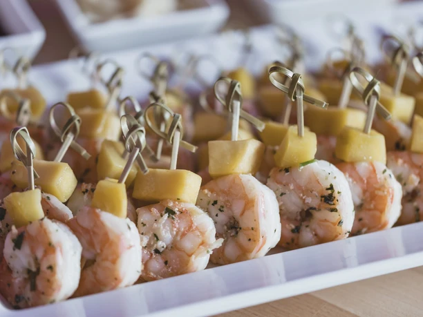 Shrimp skewers with pineapple cubes on a white serving platter
