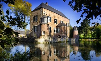 Außenansicht Kasteel Erenstein Schloss mit zwei Türmern rechts und links, die niedriger sind als das restliche Gebäude. Es liegt in einem See und ringsherum sind Bäume.