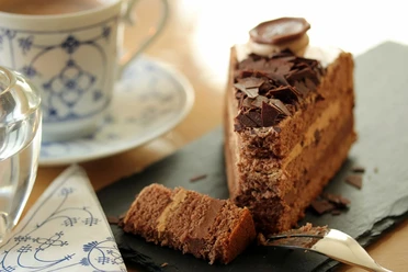 Kuchen (c) Pixabay Schokoladenkuchen mit Streuseln und eine Kaffee auf einer Untertasse links daneben.