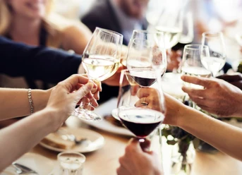 Weinbar Mehrere Personen stoßen mit Weingläsern an.