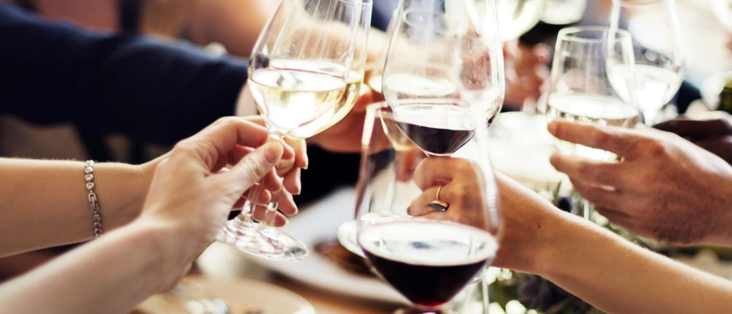 Weinbar Mehrere Personen stoßen mit Weingläsern an.