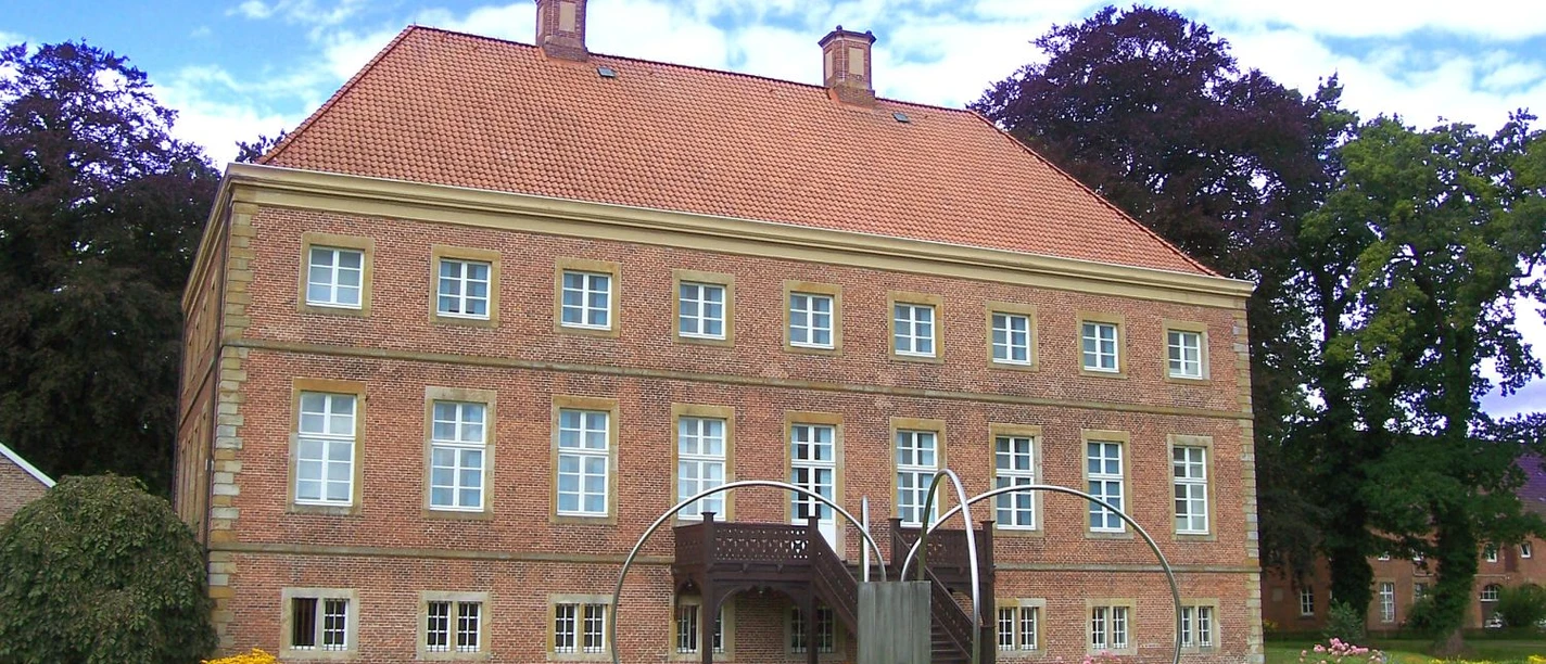 Emsland_-_Aschendorf_-_Gut_Altenkamp_-_Aussenansicht_vom_Park_auf_das_Herrenhaus.jpg Backsteinernes Herrenhaus Gut Altenkamp mit rotem Ziegeldach, gepflegtem Park und moderner Skulptur.