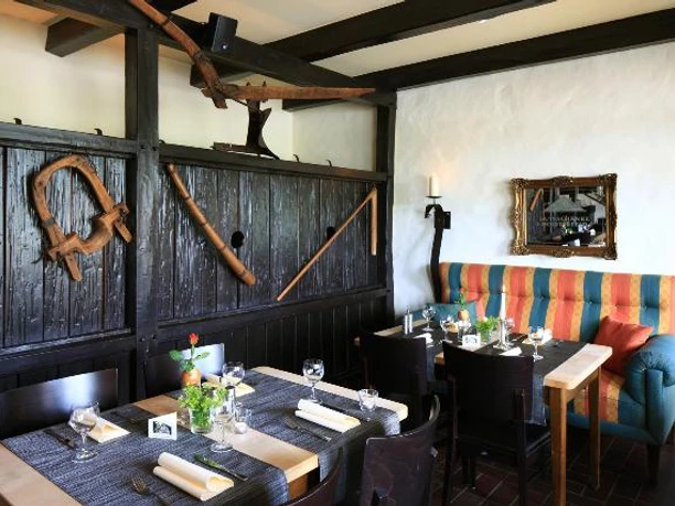 Gutsschaenke_Holsterfeld_Salzbergen_Deele.JPG Holzvertäfeltes Restaurant mit gedeckten Tischen, buntem Polstersofa und ländlicher Dekoration.