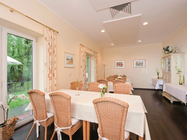 Emsbruecke_2010_Restaurant_mini.jpg Heller Speiseraum mit Korbstühlen, weißen Tischdecken und Blick auf grüne Gartenlandschaft.