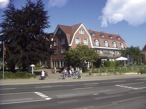 Hotel Pöker Backsteingebäude des Hotel Pöker in Meppen mit Radfahrern auf der Straße bei sonnigem Wetter