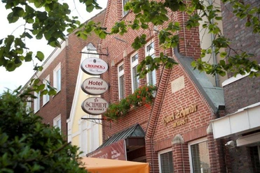Hotel Schmidt am Markt Backsteinfassade des Hotel-Restaurants Schmidt am Markt in Meppen mit schmiedeeisernem Firmenschild.