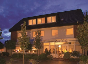 Hotel_Walker_pbg (1) Außenansicht des Hotel Walker in Papenburg bei Abenddämmerung mit warm beleuchteten Fenstern