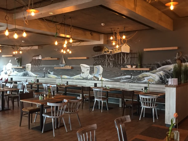 deichkrone-johanna-l-bbers-15 Holzverkleideter Gastraum mit maritimer Wandmalerei, Hängeleuchten und liebevoll gedeckten Tischen.