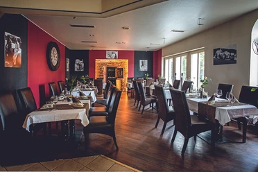 restaurant-parkhotel-lingen Modern eingerichteter Speiseraum mit gedeckten Tischen, Ledersesseln und beleuchtetem Kaminbereich
