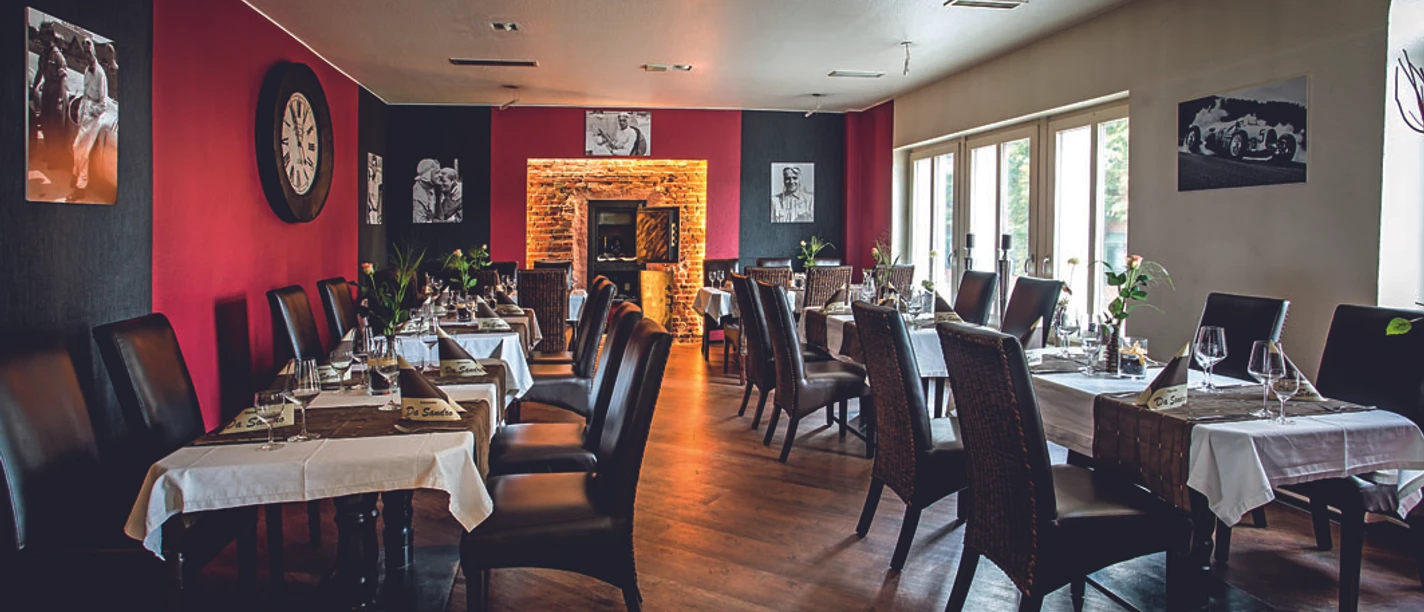 restaurant-parkhotel-lingen Modern eingerichteter Speiseraum mit gedeckten Tischen, Ledersesseln und beleuchtetem Kaminbereich