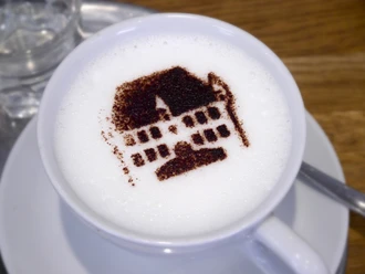 Koffie met opgeschuimde melk, versierd met de cacao-afbeelding van een historisch gebouw.