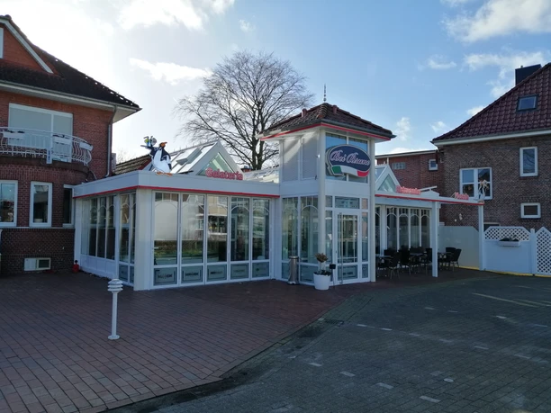 Eiscafé & Pizzeria bei Bruno Rhauderfehn Eiscafé und Pizzeria Bei Bruno mit weißer Glasfassade, rotem Schriftzug und Pinguinfigur auf dem Dach in Rhauderfehn