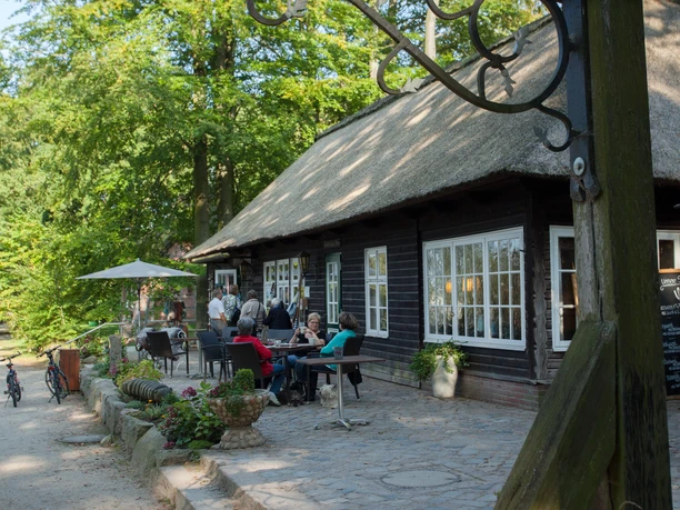 milchhalle-wilsede-bispingen Rasthaus mit Reetdach und Sonnenterrasse, eingebettet in Grünen, lädt Fahrradfahrer zu Pausensnack ein.