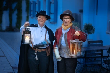 Mit Nachtwächter & Türmer unterwegs Zwei Nachtwächter mit Laternen in einer Gasse bei Abendlicht