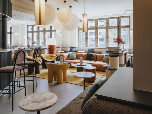Lounge Helle Lounge mit modernen Sitzmöbeln, runden Tischen und großen Papierleuchten