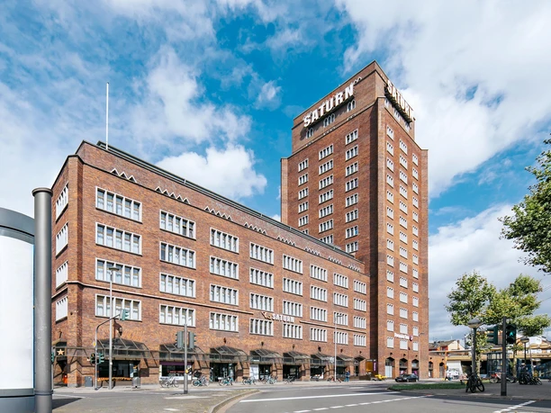 Außenansicht Backsteingebäude mit hohem Turm an Kreuzung unter blauem Himmel
