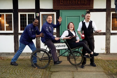 Historisches Gasthaus Buschkamp Teamfoto.jpg Mitarbeitende des Historischen Gasthaus Buschkamp auf einem altertümlichen Fahrrad