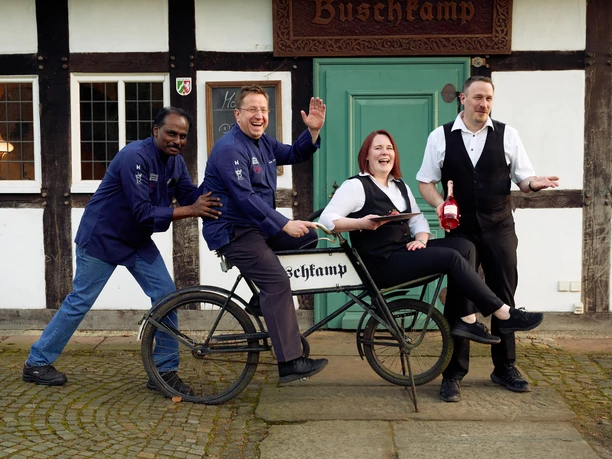 Historisches Gasthaus Buschkamp Teamfoto.jpg Mitarbeitende des Historischen Gasthaus Buschkamp auf einem altertümlichen Fahrrad