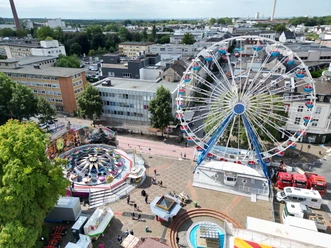 Pfingstkirmes Luftaufnahme einer Kirmes mit großem Riesenrad, Fahrgeschäften und umgebenden Stadtgebäuden