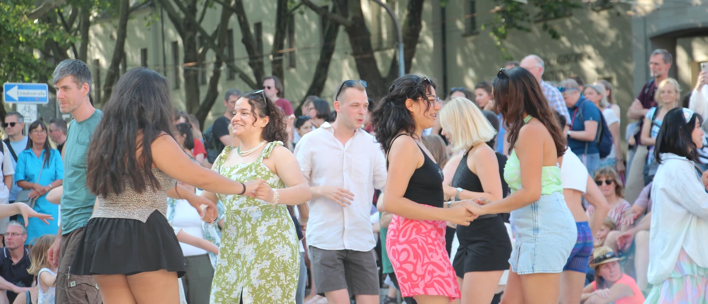 Fête de la Musique 2025 Titelbild Besucher:innen tanzen bei der Fête de la Musique 2025 in Jena vor Publikum unter freiem Himmel.