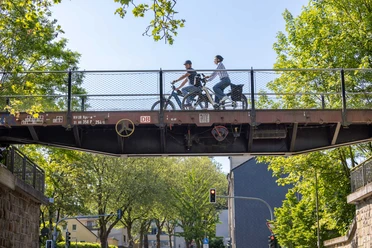 Waggonbrücke in Heiligenhaus Radfahrer_innen überqueren eine historische Waggonbrücke in Heiligenhaus, umgeben von viel Grün.