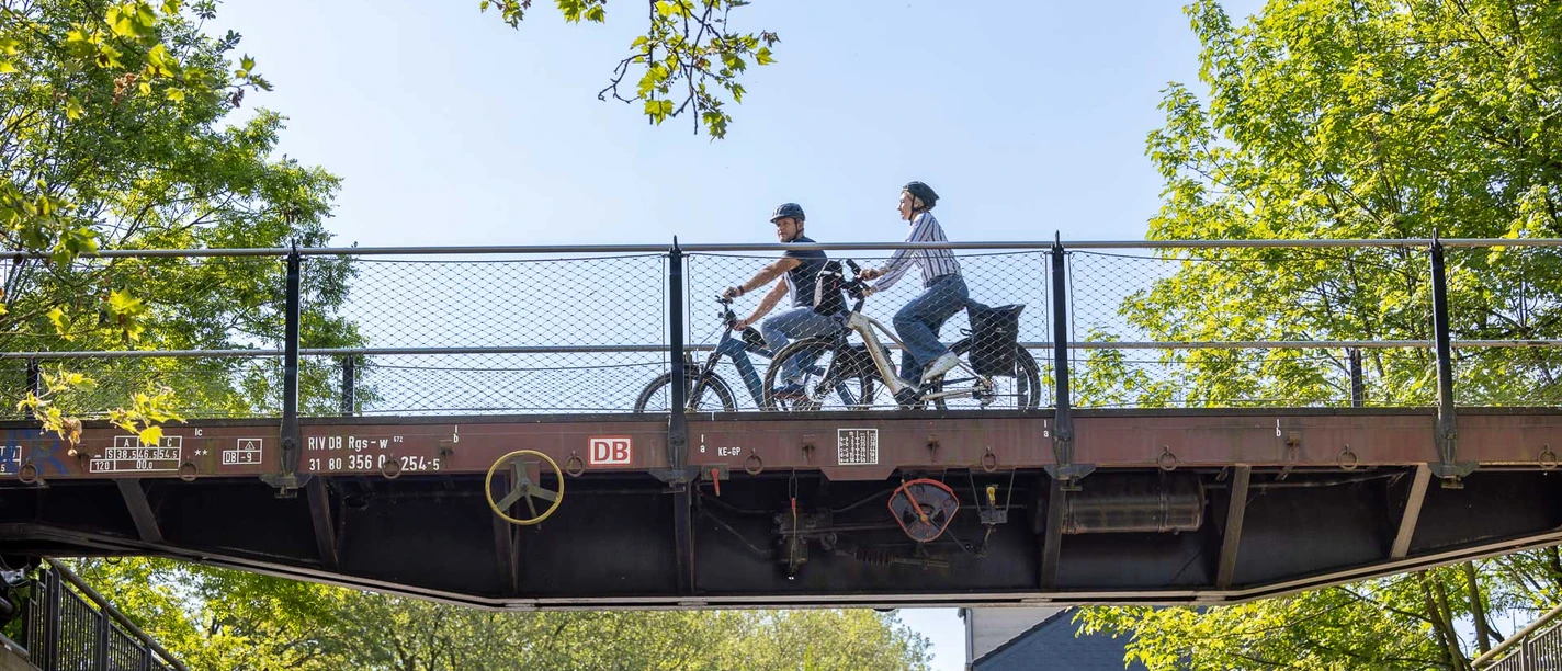 Waggonbrücke in Heiligenhaus Radfahrer_innen überqueren eine historische Waggonbrücke in Heiligenhaus, umgeben von viel Grün.