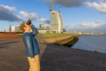 S8367-Bearbeitet (c) Helmut Gross_Erlebnis Bremerhaven_WEB.jpg Fernglasmann-Skulptur an der Weserpromenade vor dem Atlantic Hotel Sail City in Bremerhaven.