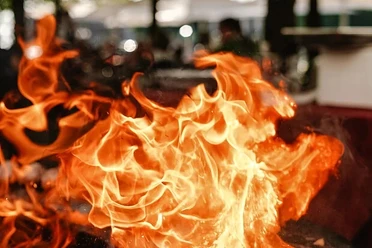 Bella BBQ Lodernde orange Flammen über einem Grill bei einer Outdoor‑Kochszene