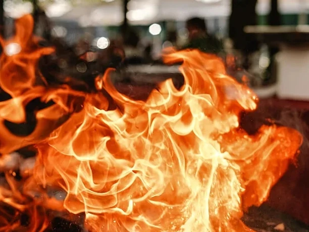 Bella BBQ Lodernde orange Flammen über einem Grill bei einer Outdoor‑Kochszene